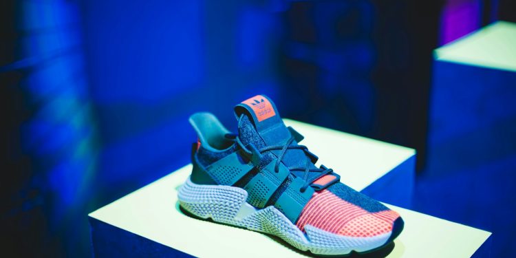 blue, pink, and white adidas athletic shoe on white display table