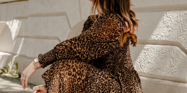 woman in brown and black leopard print dress holding white leather handbag