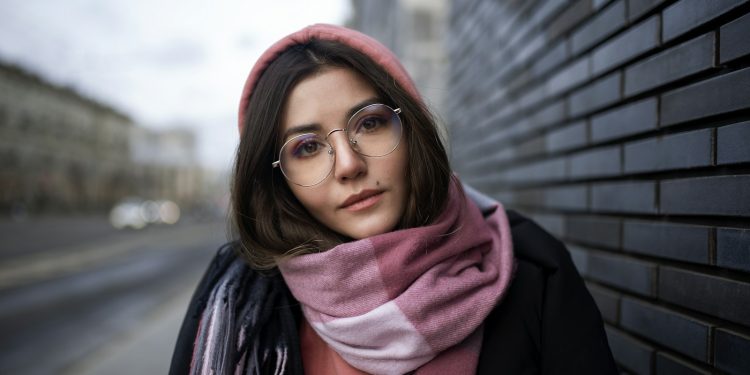 woman in black coat wearing red scarf and black framed eyeglasses