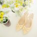 pair of women's beige pointed-toe slingback pumps with ribbons near flower vase