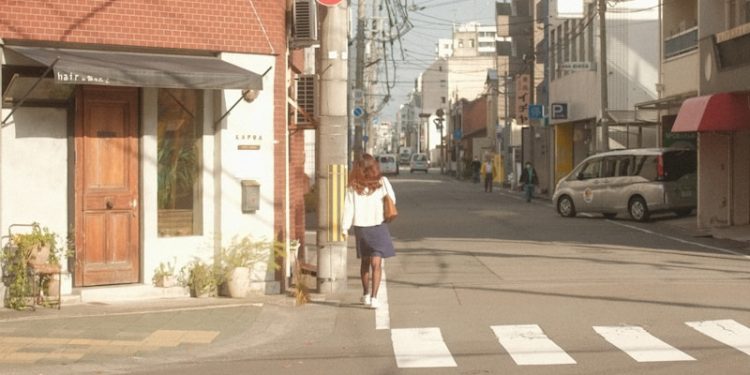 a woman walking down a street next to a traffic light