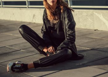 woman in black leather jacket and black pants sitting on floor