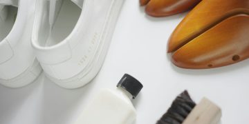 a pair of white shoes next to a white shoe brush